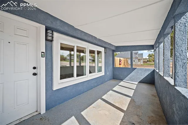 a view of an empty room with a kitchen and a window
