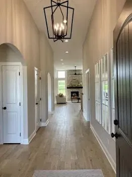 an empty room with wooden floor mirror and windows