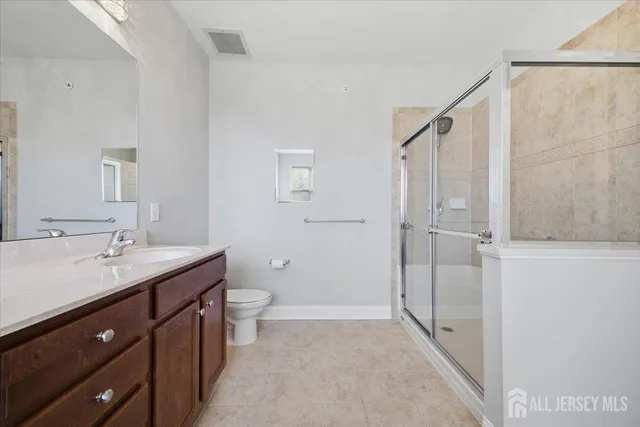 a spacious bathroom with a double vanity sink toilet mirror and shower