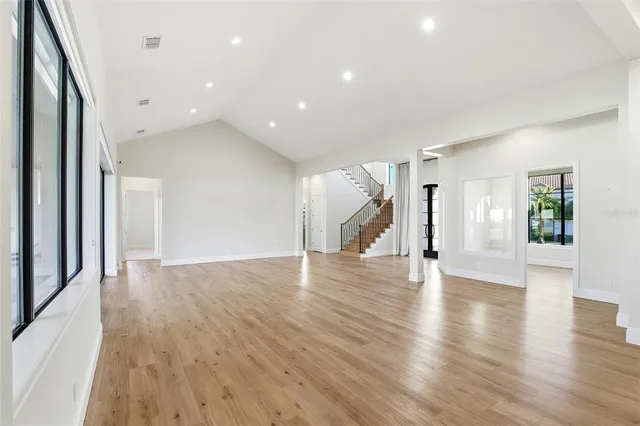 a view of an empty room with wooden floor and a large window