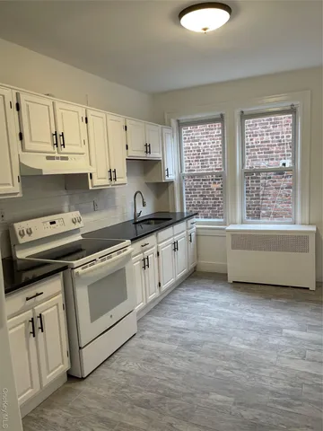 a kitchen with granite countertop a sink cabinets and stainless steel appliances