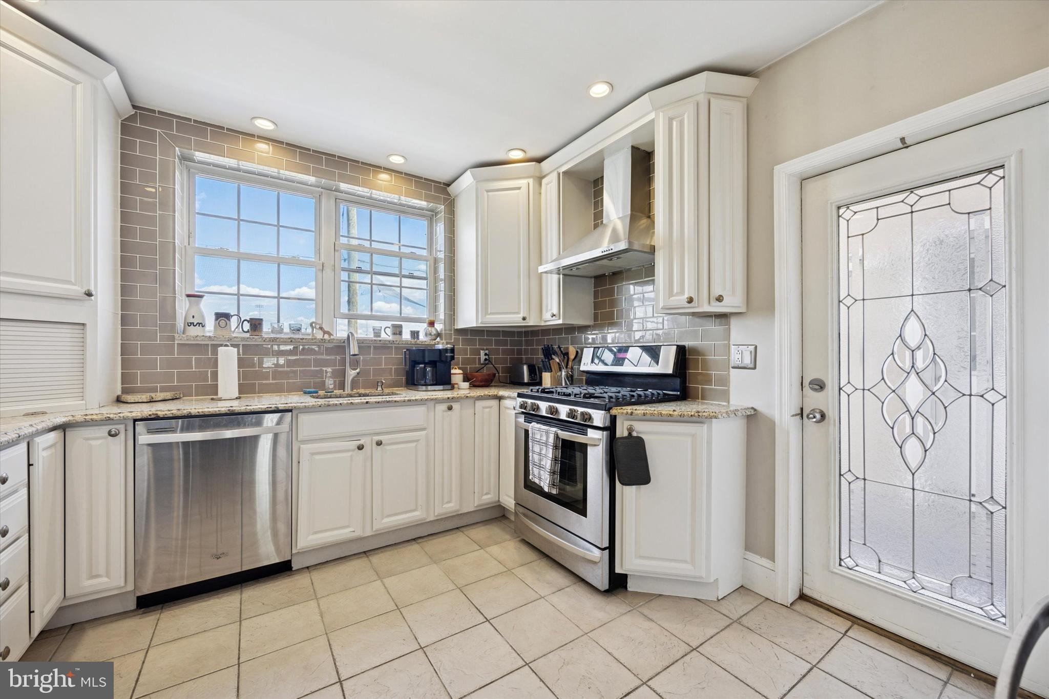 2935 South 13th Street Philadelphia, PA 19148 - Photo 5 of 24 a white kitchen with stainless steel appliances granite countertop a stove a sink and a microwave