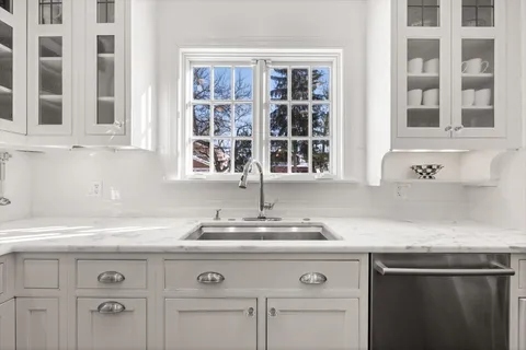a kitchen with granite countertop white cabinets and a sink
