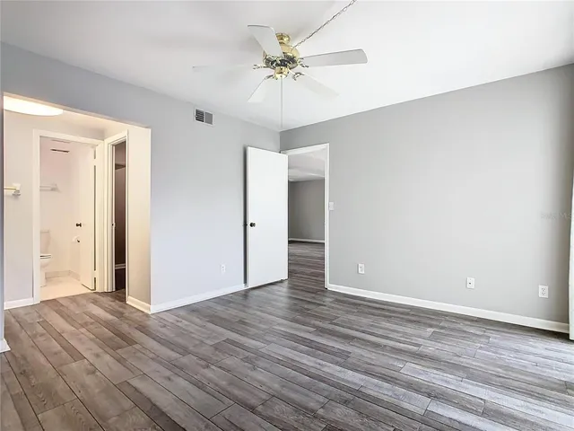 an empty room with wooden floor and ceiling fan