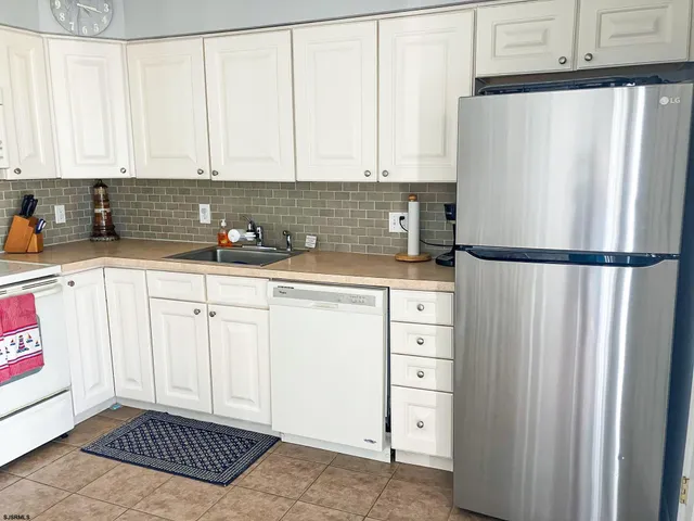 a kitchen with white cabinets and refrigerator