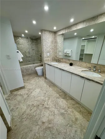 a bathroom with a granite countertop sink a toilet and shower