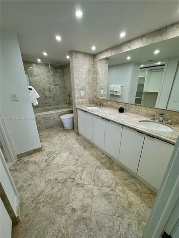 a bathroom with a granite countertop sink a toilet and shower