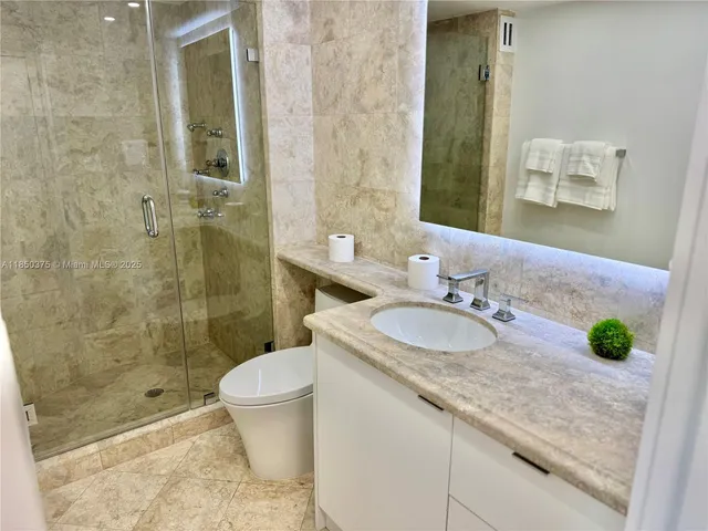 a bathroom with a granite countertop sink toilet and shower