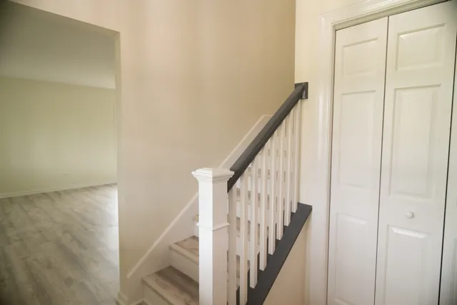 a view of staircase with wooden floor and white walls