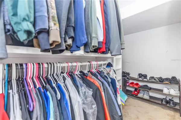 a view of walk in closet with clothes and shoes