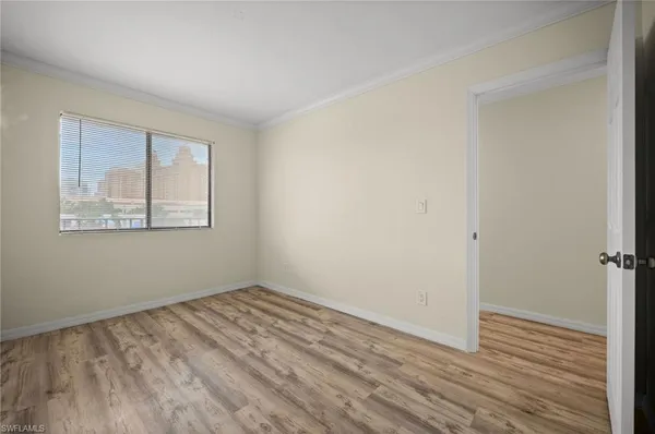 a view of an empty room with wooden floor and a window