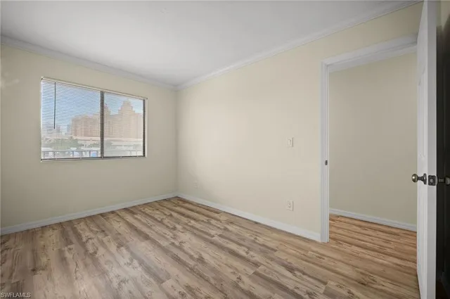 a view of an empty room with wooden floor and a window
