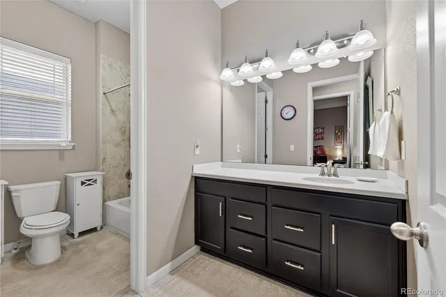 a bathroom with a granite countertop sink a toilet and a mirror
