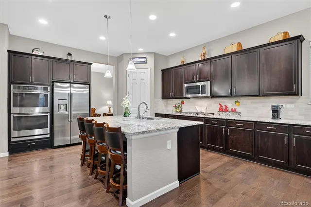 a kitchen with stainless steel appliances granite countertop a stove top oven a sink dishwasher a dining table and chairs