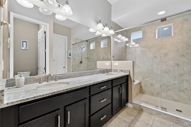 a bathroom with a granite countertop sink a large mirror and a shower