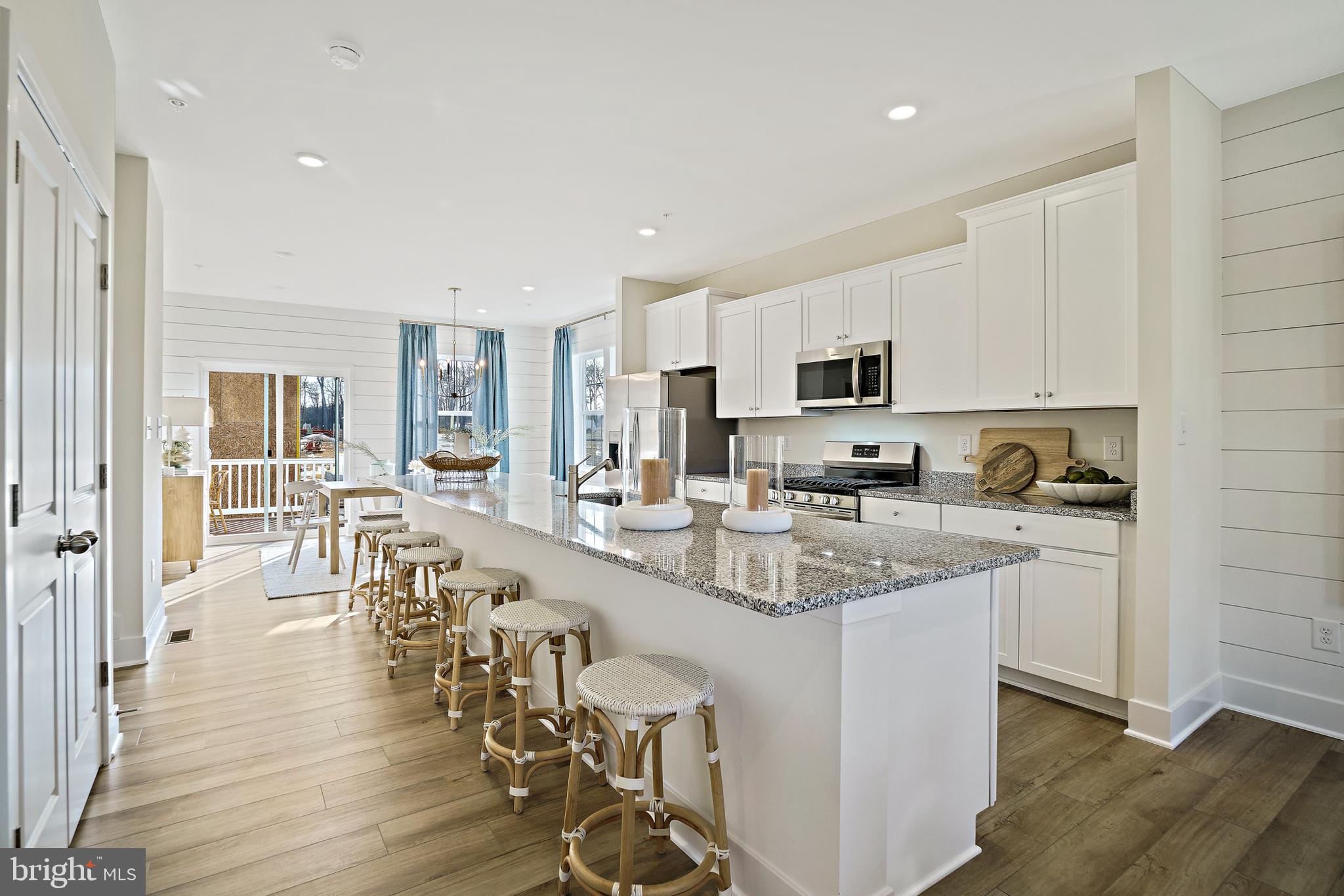 23600 Crosswinds Way California, MD 20619 - Photo 23 of 55 a kitchen with stainless steel appliances granite countertop a stove top oven a sink a dining table and chairs with wooden floor