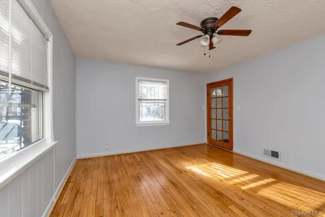 a view of empty room with wooden floor and fan