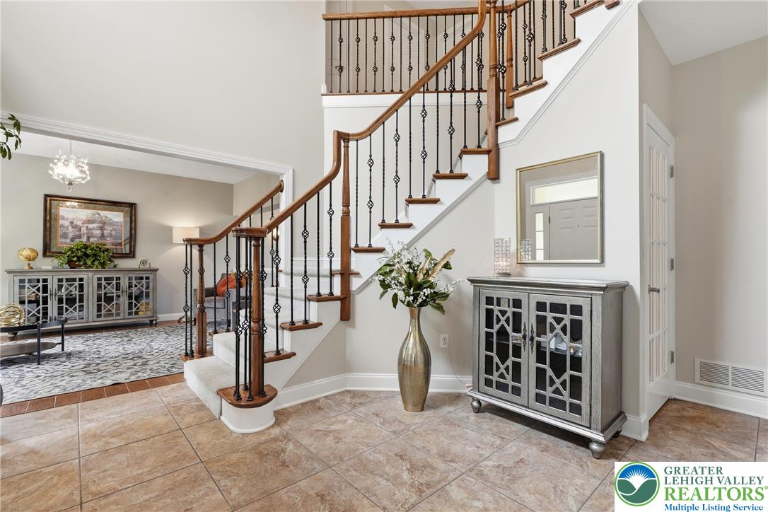 245 East Dell Road Bath, PA 18014 - Photo 4 of 99 A grand entryway features a curved staircase with intricate wrought iron balusters and warm wood railings.