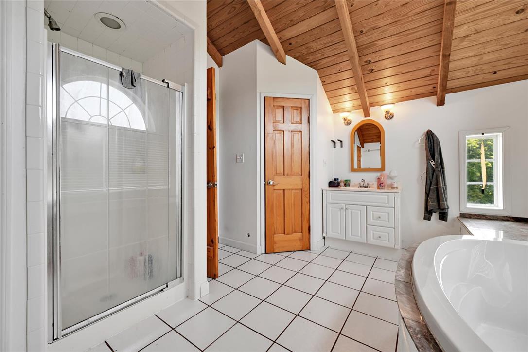 101 Conrad Road Fleetwood, PA 19522 - Photo 14 of 42 Natural wood vaulted ceilings crown a pristine tiled bathroom, featuring a standalone shower and a clean, inviting tub.