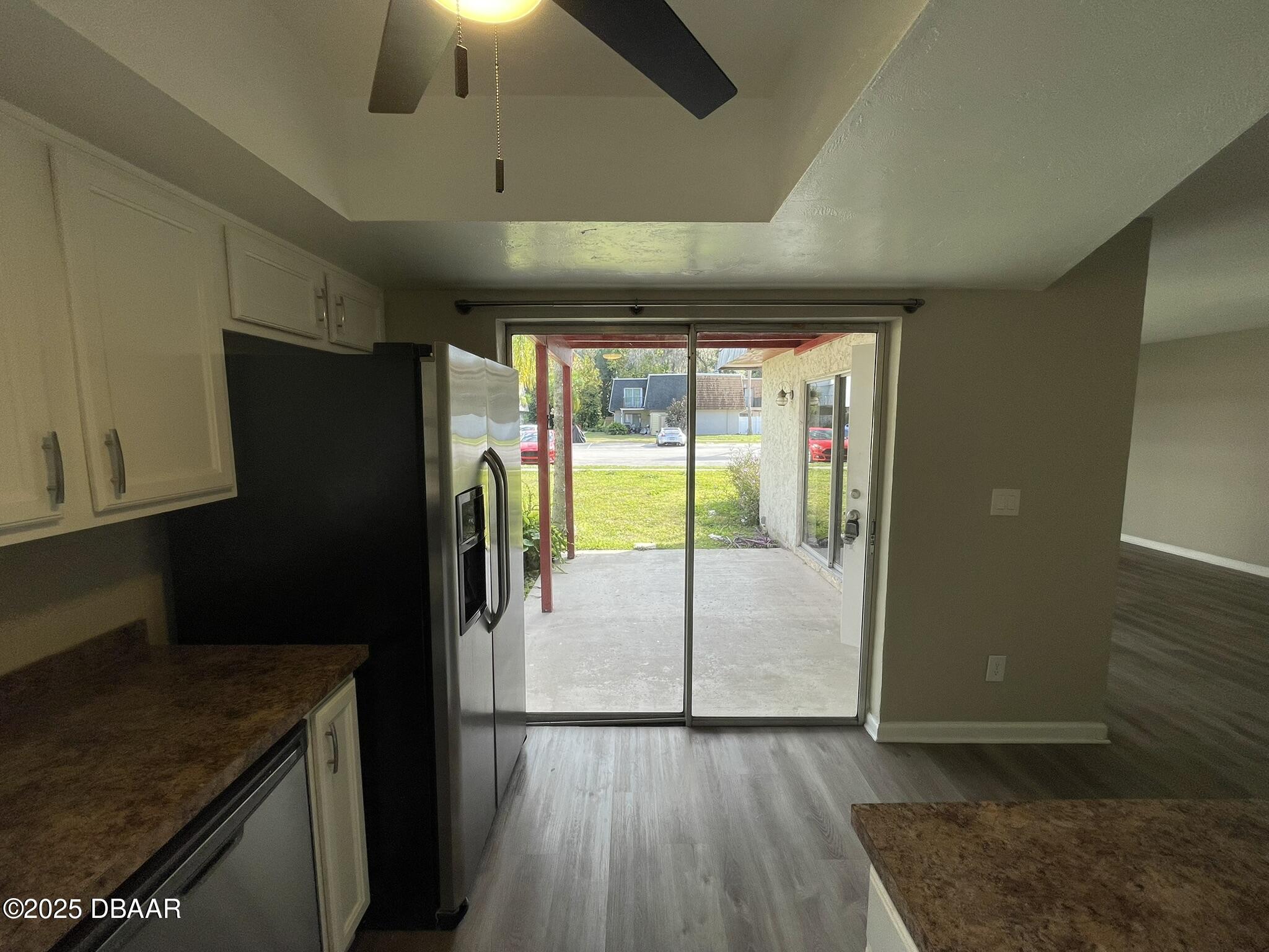 97 Springwood Square Port Orange, FL 32129 - Photo 11 of 23 a view of a refrigerator in kitchen and an empty room with wooden floor