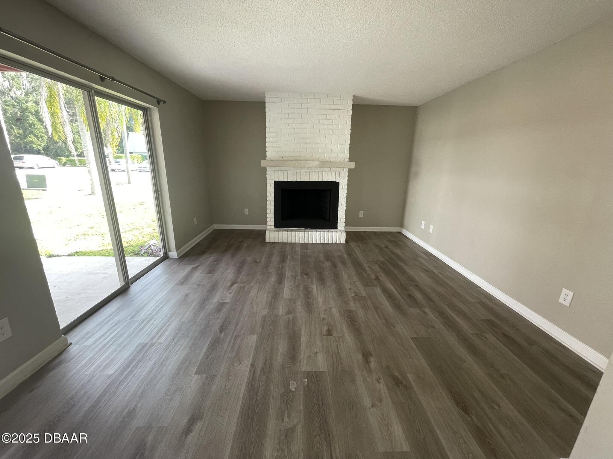 97 Springwood Square Port Orange, FL 32129 - Photo 5 of 23 an empty room with wooden floor and a fireplace