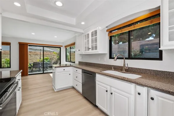 a large white kitchen with granite countertop a large window and a sink