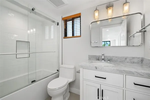 a bathroom with a granite countertop sink toilet mirror and shower