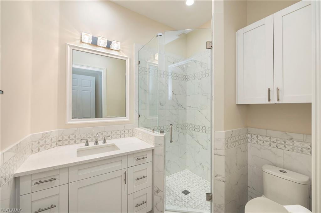 5025 Maxwell Circle, Unit 2 Naples, FL 34105 - Photo 16 of 24 a bathroom with a shower sink vanity and mirror