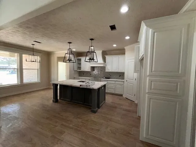a large kitchen with a large counter top space a sink stainless steel appliances and cabinets