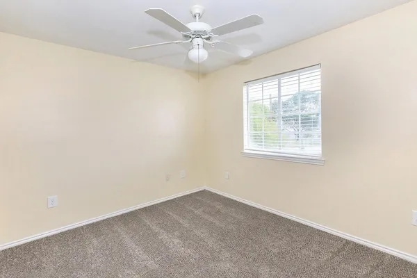 an empty room with windows and ceiling fan