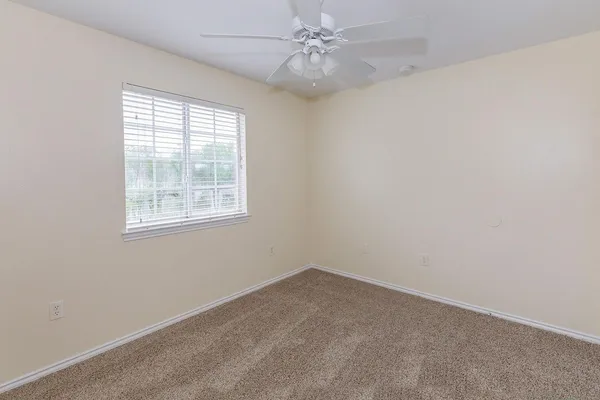 an empty room with a window and ceiling fan