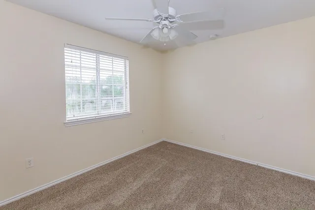 an empty room with a window and ceiling fan