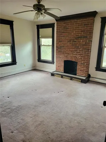 an empty room with windows and fireplace