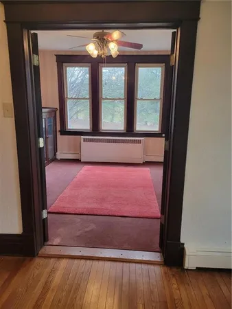 a view of empty room with wooden floor and fan