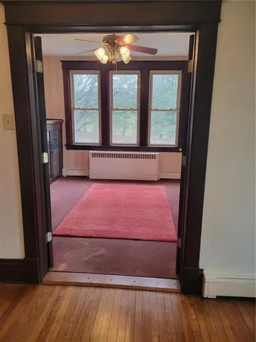 a view of empty room with wooden floor and fan