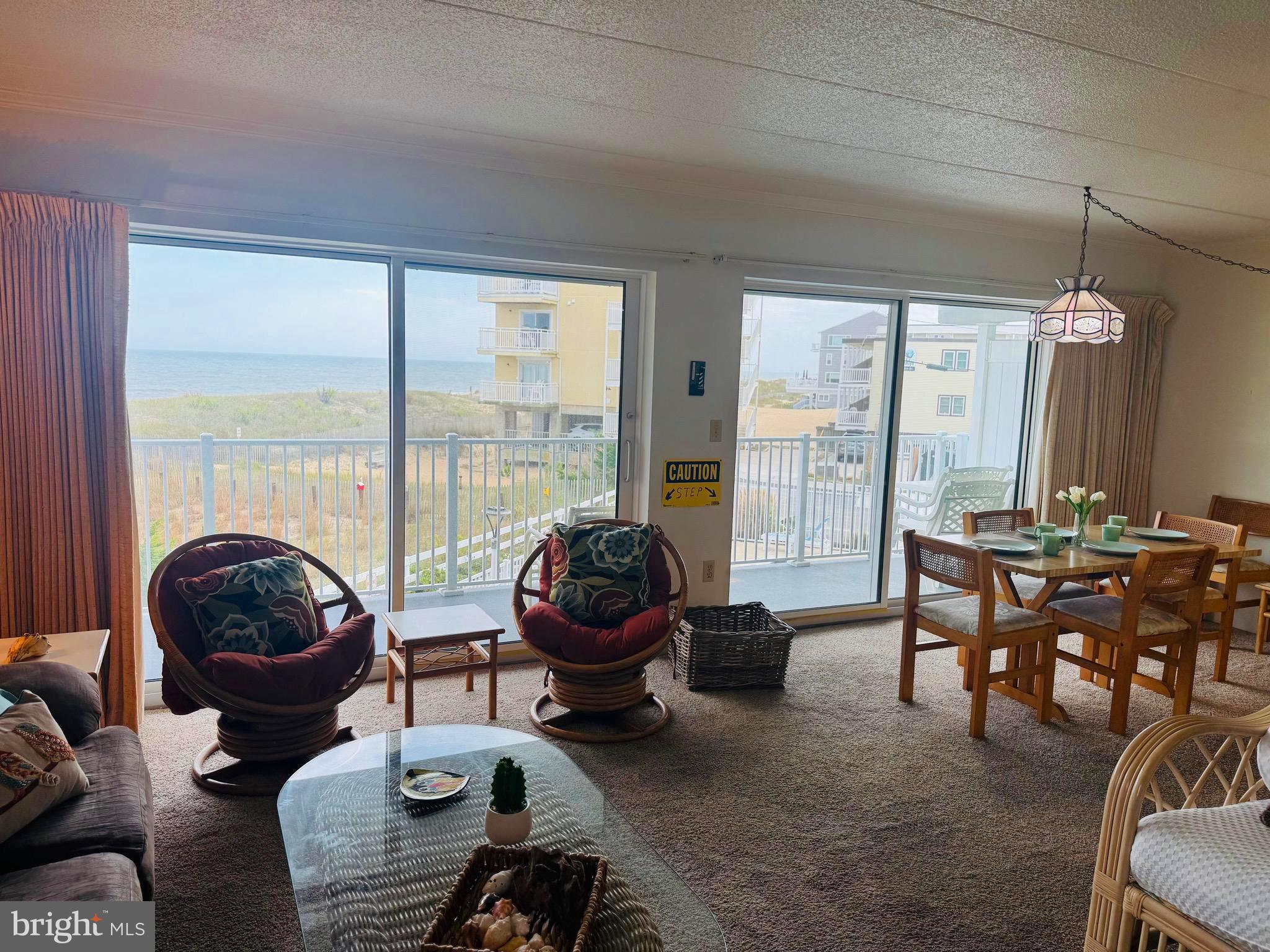 2 80th Street, Unit 212 Ocean City, MD 21842 - Photo 7 of 27 a living room with furniture a rug a large window and a chandelier