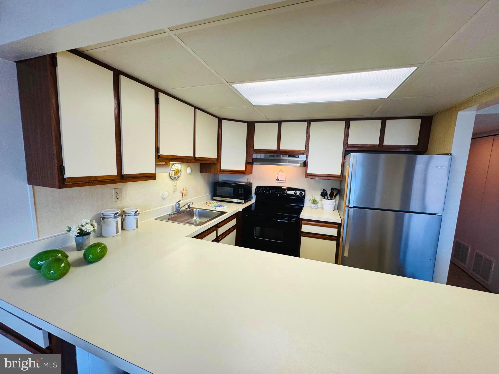 2 80th Street, Unit 212 Ocean City, MD 21842 - Photo 9 of 27 a kitchen with stainless steel appliances a refrigerator sink and wooden cabinets