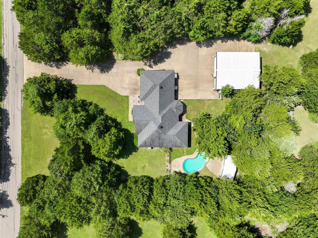 401 Rugged Drive Red Oak, TX 75154 - Photo 2 of 40 Expansive property featuring a large residence with a dark shingle roof, a detached outbuilding with a light-colored roof, a swimming pool with a stone patio surround, a concrete driveway, and mature landscaping