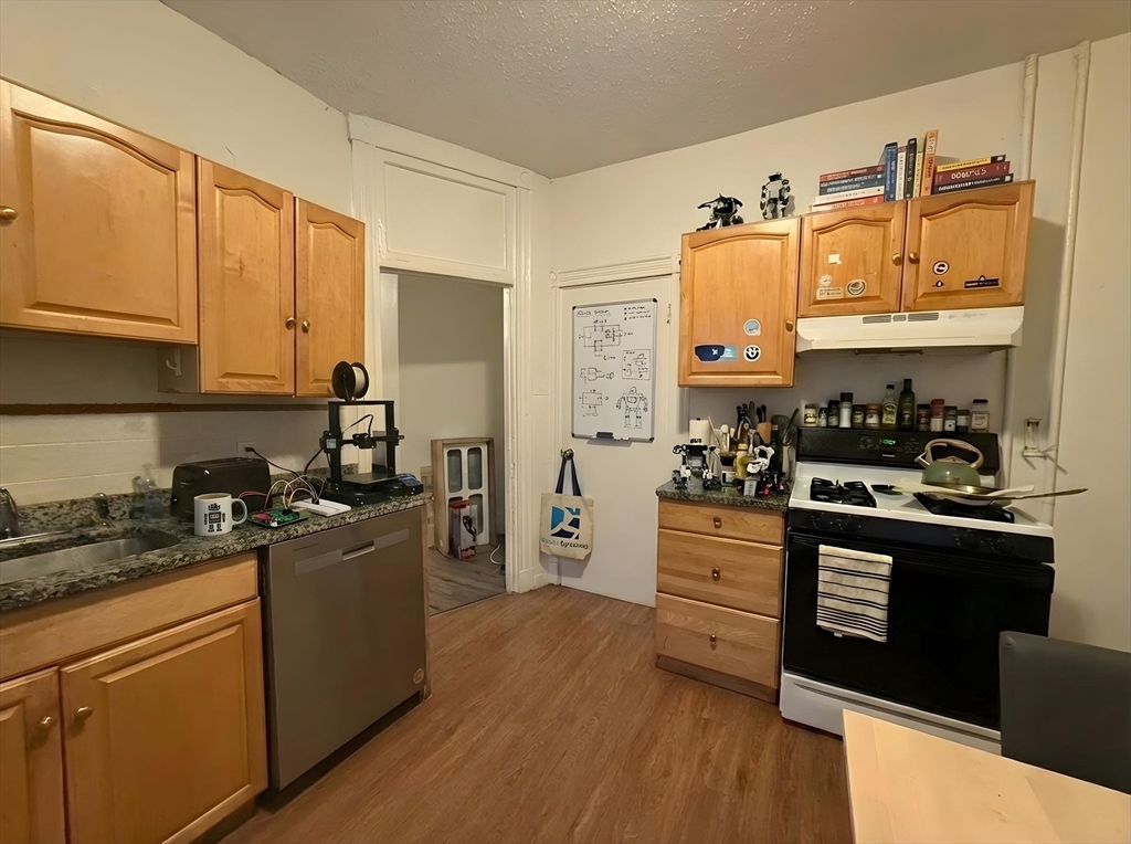 34 Cherokee Street, Unit 3 Boston, MA 02120 - Photo 2 of 15 a kitchen with stainless steel appliances granite countertop a stove top oven a sink dishwasher and white cabinets with wooden floor