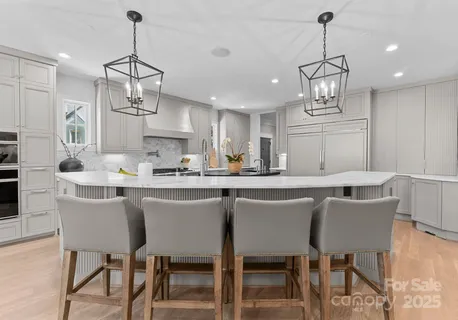 a kitchen with stainless steel appliances kitchen island granite countertop a dining table chairs and white cabinets
