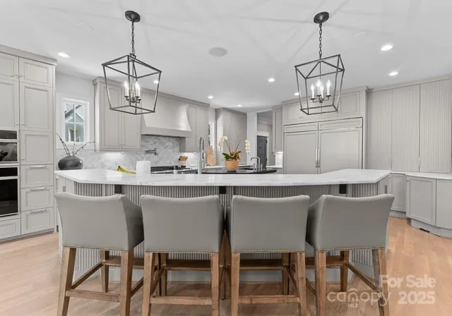 a kitchen with stainless steel appliances kitchen island granite countertop a dining table chairs and white cabinets