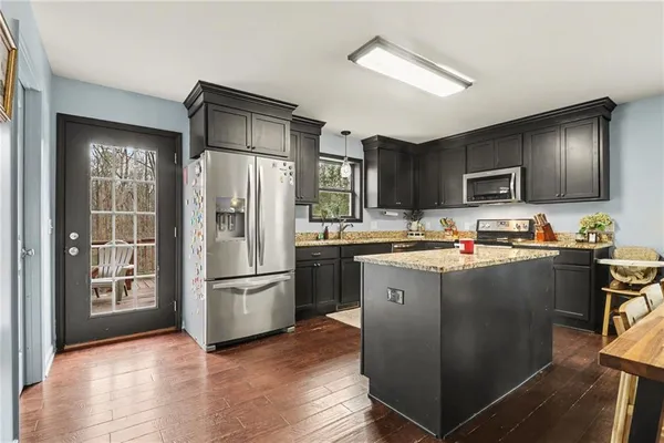 a kitchen with stainless steel appliances granite countertop a refrigerator stove and a sink with wooden floor