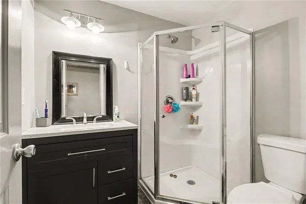a bathroom with a shower a sink and a mirror with toilet