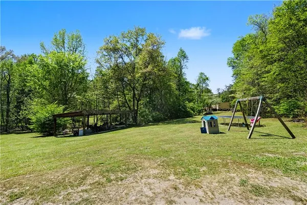 a view of pool with a bench and trees