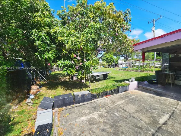 a view of a yard with a table and chairs under an umbrella