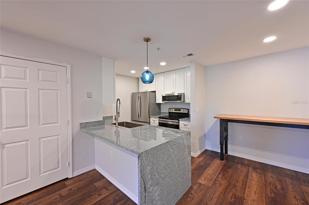 8809 Manor Loop, Unit 106 Lakewood Ranch, FL 34202 - Photo 12 of 40 a kitchen with kitchen island white cabinets and refrigerator