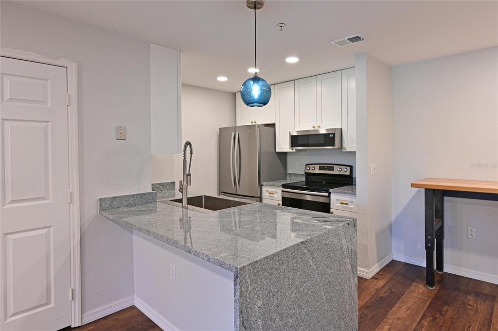 8809 Manor Loop, Unit 106 Lakewood Ranch, FL 34202 - Photo 13 of 40 a kitchen with kitchen island a counter space a sink appliances and cabinets