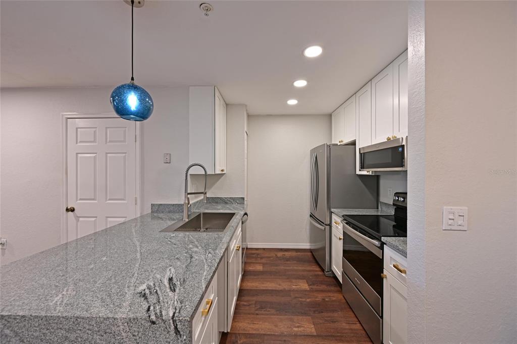 8809 Manor Loop, Unit 106 Lakewood Ranch, FL 34202 - Photo 14 of 40 a kitchen with stainless steel appliances granite countertop a sink refrigerator and stove
