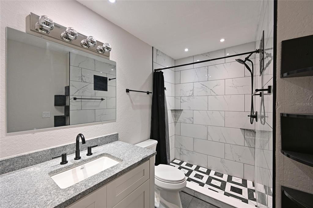 8809 Manor Loop, Unit 106 Lakewood Ranch, FL 34202 - Photo 24 of 40 a bathroom with a sink a toilet a mirror and shower