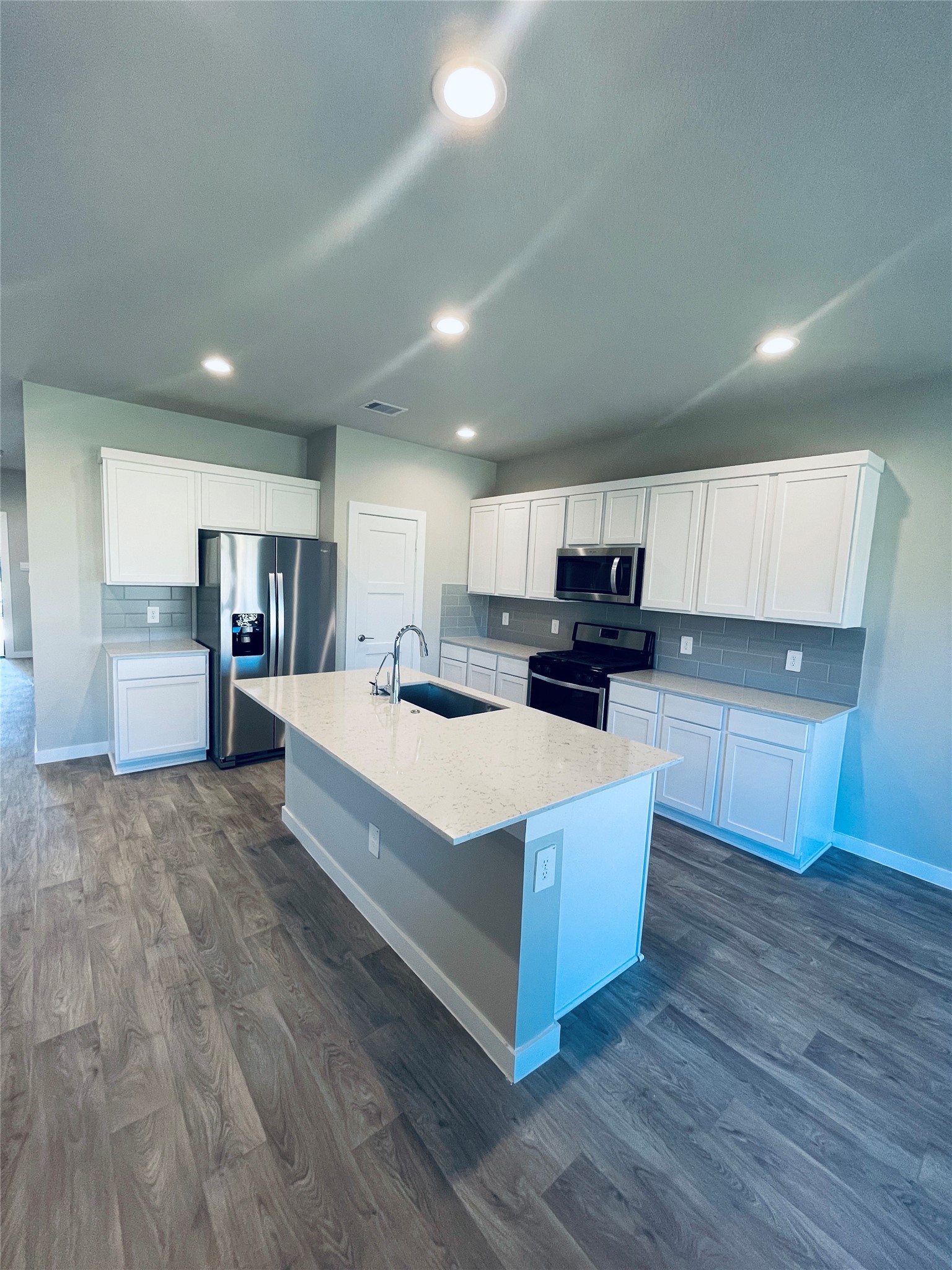 14238 Wonder Lake Lane Conroe, TX 77384 - Photo 6 of 20 a large white kitchen with kitchen island a sink dishwasher a oven and a large island with wooden floor
